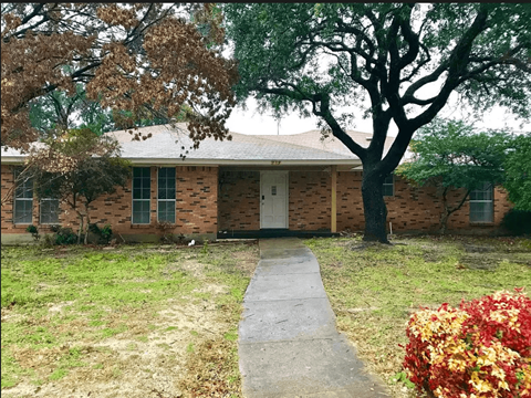 a small brick house with a sidewalk in front of it